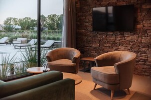 Un área de estar con sillones de cuero, un sofá y un televisor de pantalla plana montado en una pared de piedra.