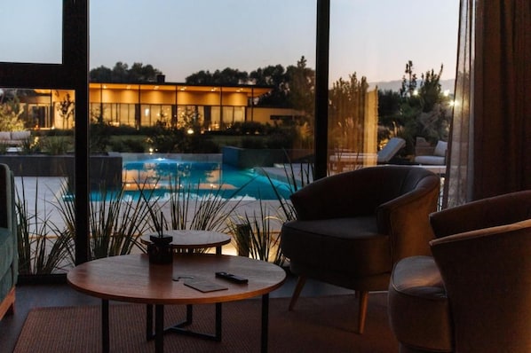 A modern interior with a pool view, a round table, and a sofa. - Legado Wine Lodge (Maipú)