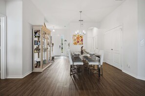 A spacious dining area with a long table and modern chairs, a glass-fronted display cabinet, and a chandelier. - Disney Princess Suite, Family Home, Sleeps 12 (Davenport)