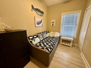 A bedroom with a bed, dresser, artwork, and a window with blinds. - Pet-Friendly Ocean Lakes 3BR | Golf Cart | Sleeps 5 (Myrtle Beach)