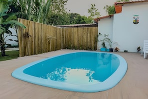 A swimming pool with a wooden fence and potted plants. - Apartamento 5 com 2 suítes 450m da praia (Santa Cruz Cabrália)