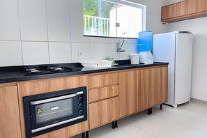 A modern kitchen with a built-in microwave, a gas stove, and a water dispenser. - Apartamento 5 com 2 suítes 450m da praia (Santa Cruz Cabrália)