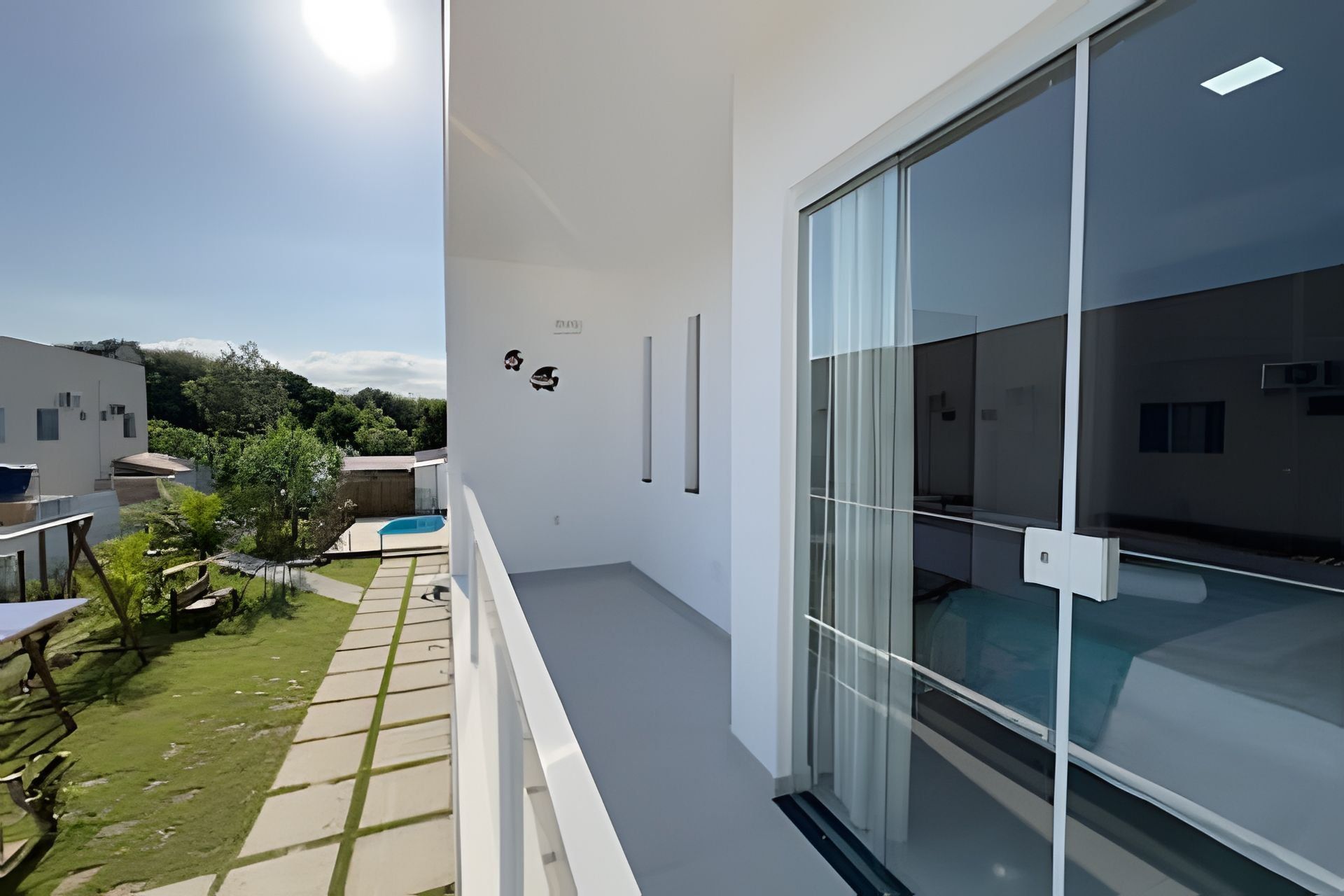 Varanda moderna com porta de vidro, piscina pequena e vista para área residencial.