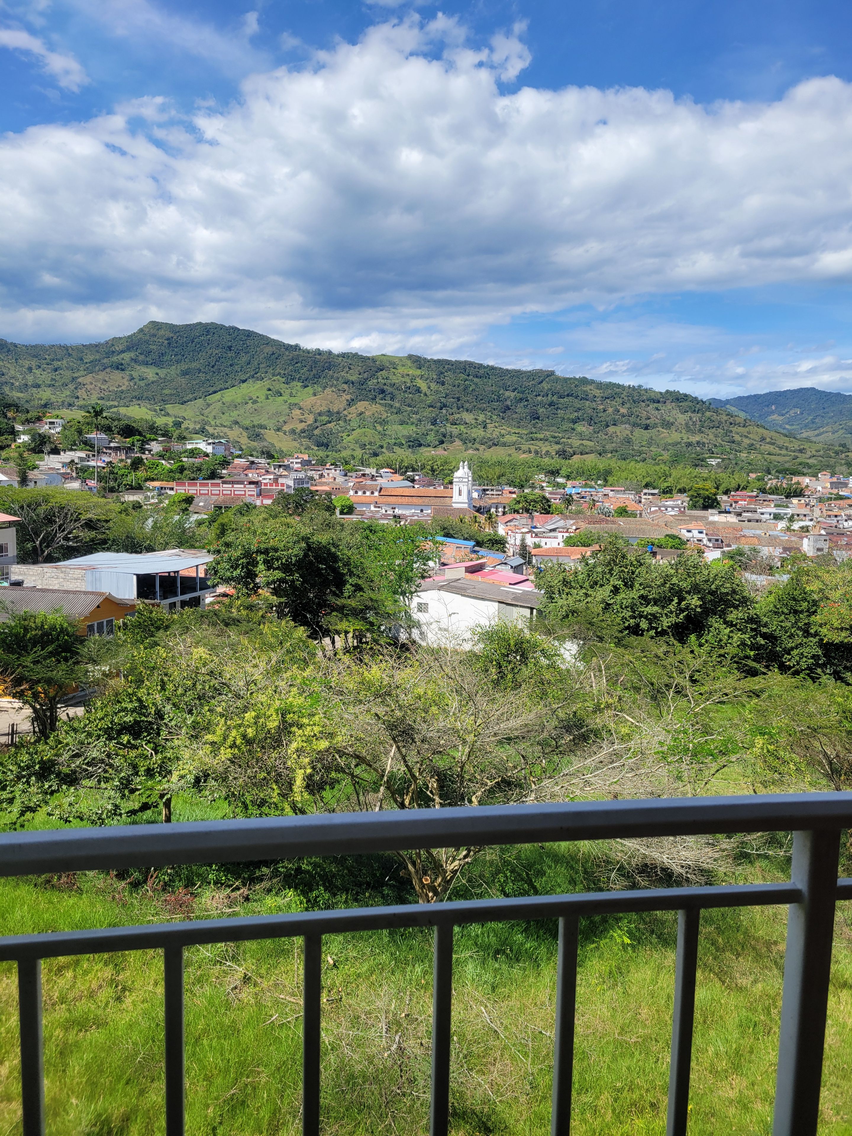 Un pueblo con una mezcla de edificios residenciales y comerciales, rodeado de colinas verdes y exuberantes.