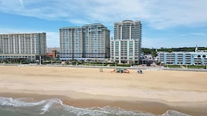 A beachfront hotel with multiple high-rise buildings, a sandy beach, and a playground area.