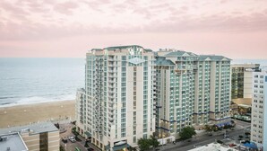 A high-rise hotel with multiple balconies, a beach view, and a prominent hotel sign. - Oceanaire Virginia Beach - 1BR Ocean View Suite, Full Kitchen + Balcony (Virginia Beach)
