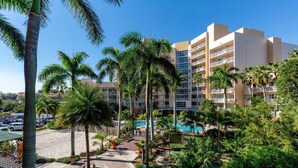 Un hotel con varios pisos, piscina y palmeras.