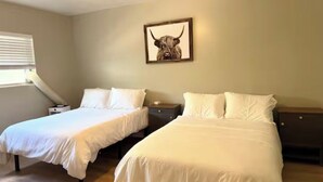 A bedroom with two beds, a ceiling fan, and a framed picture on the wall. - River House (Logan)