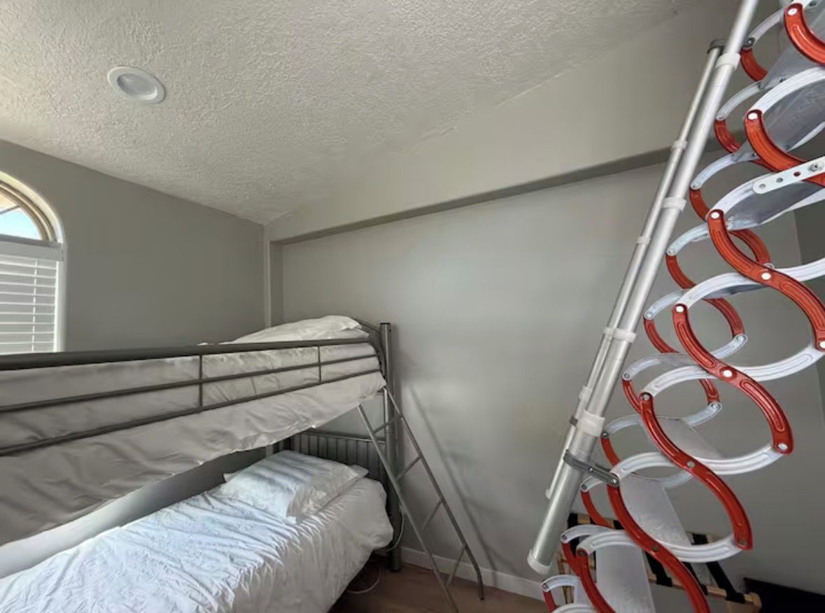 A room with a bunk bed, a ladder, and a drying rack.