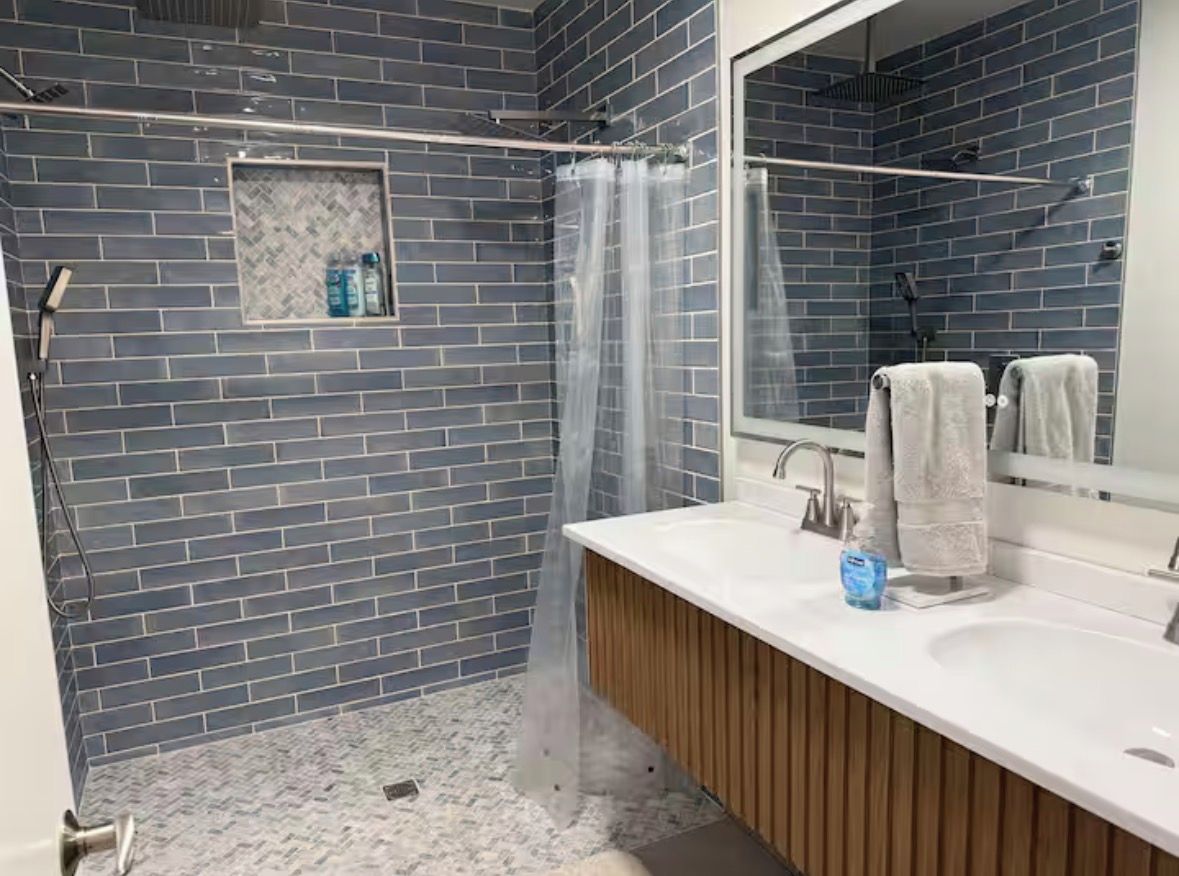 A bathroom with a shower, a sink, and a mirror.