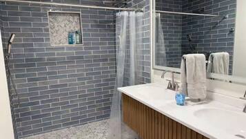 A bathroom with a shower, a sink, and a mirror.