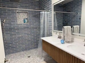 Ein Badezimmer mit Dusche, Waschbecken und Spiegel.