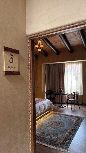 Un dormitorio con cama, una mesa, sillas, alfombra y candelabro.