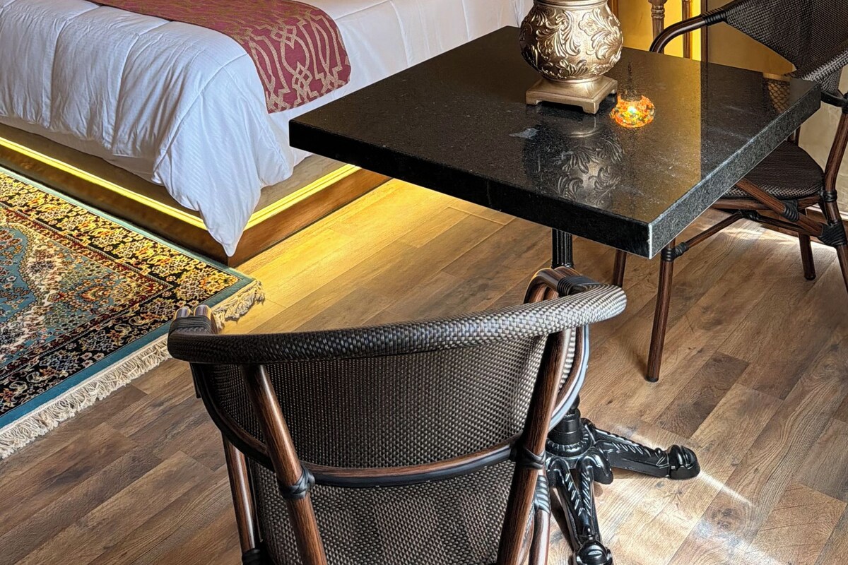 A hotel room with a large bed, a dining table, and a chair.