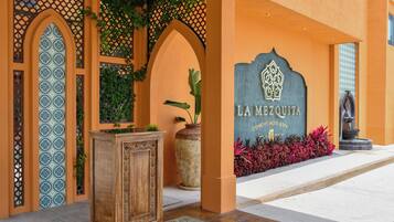A hotel entrance with a decorative archway, a sign reading 'LA MEZQUITA CONCEPT HOTEL & SPA', and a statue.