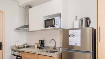 Una cocina moderna con un refrigerador de acero inoxidable, un microondas y una cafetera sobre la encimera.