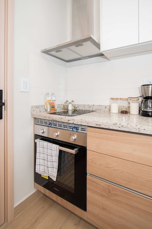 A kitchen with a built-in oven, a stovetop, and a range hood. There are jars on the counter and a coffee maker. - Corporate Stays - Matrisa - 902 (Asunción)
