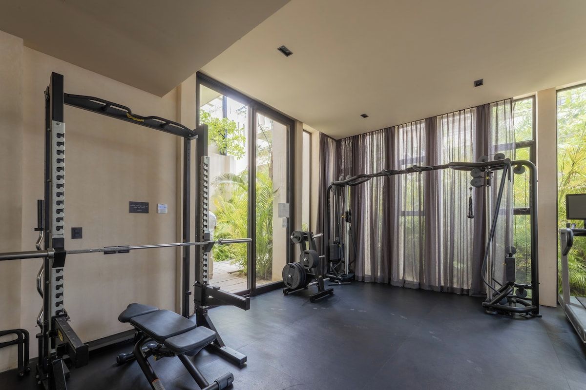 A gym with a squat rack, bench press, and various weight machines.