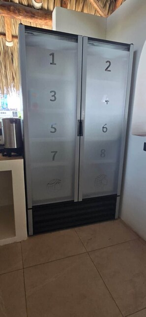 Conjunto de portas duplas com painéis numerados, provavelmente indicando números de quarto, em um ambiente com piso ladrilhado e uma lixeira visível.