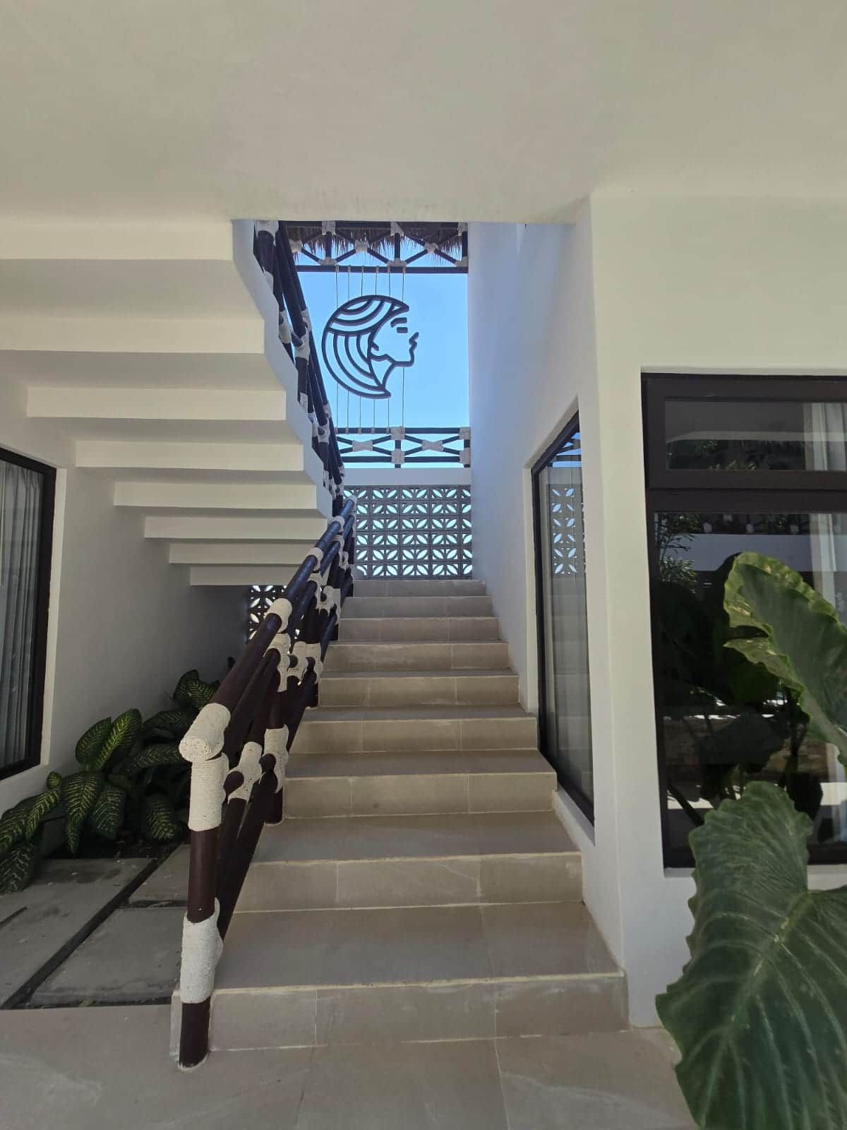 Eine moderne Treppe mit einem geometrischen Geländerdesign, die zu einem Balkon mit einer verzierten Kopfsilhouette führt.