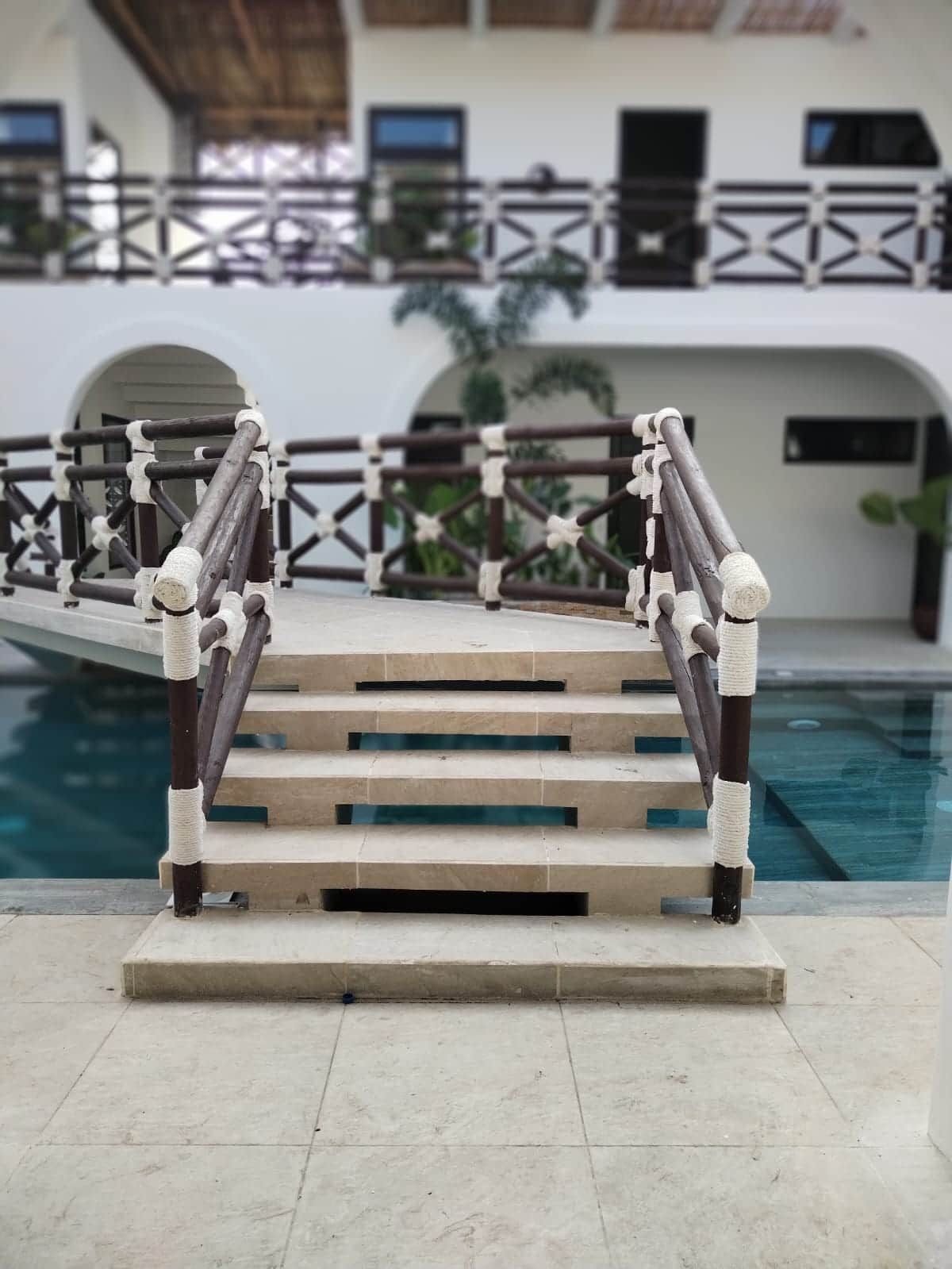 A poolside area with a wooden staircase leading to a balcony.