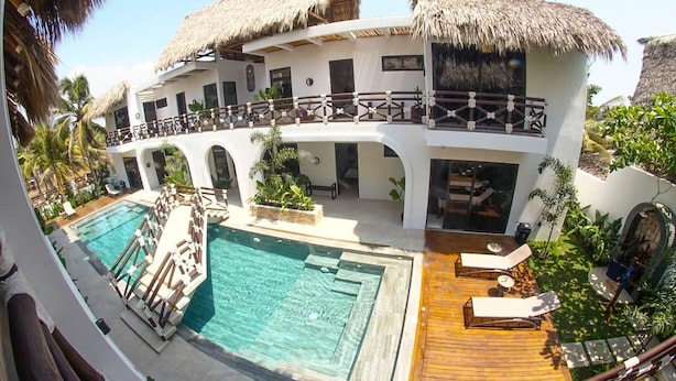 Ein Resort mit Pool, Liegestühlen und einem Gebäude mit Reetdach.