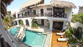 Un resort con piscina, sillas de descanso y una construcción de techo de paja.