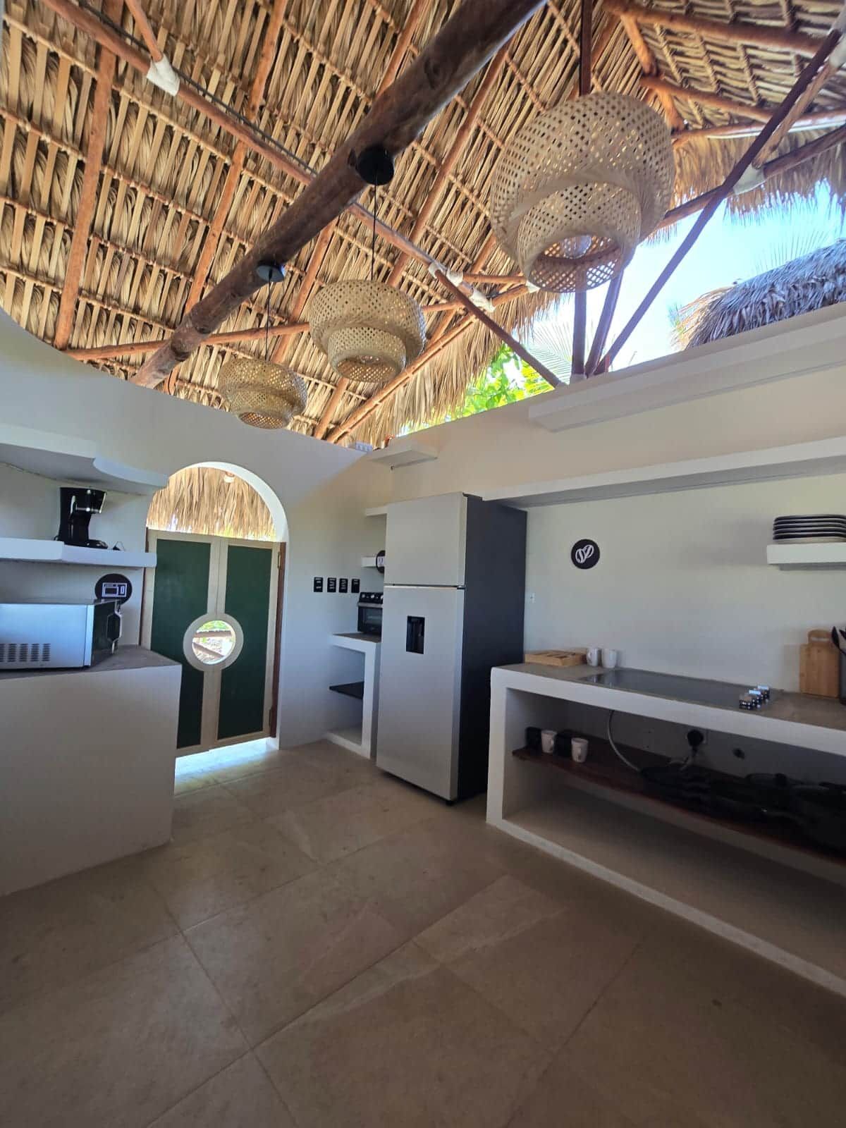 A modern kitchen with a thatched roof, white cabinetry, and a built-in oven.