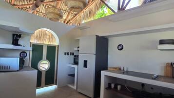 A modern kitchen with a thatched roof, white cabinetry, and a built-in oven.