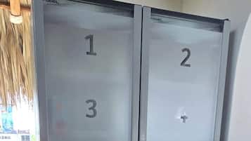 Conjunto de portas duplas com painéis numerados, provavelmente indicando números de quarto, em um ambiente com piso ladrilhado e uma lixeira visível.