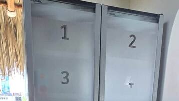 A set of double doors with numbered panels, likely indicating room numbers, in a room with a tiled floor and a visible trash bin.