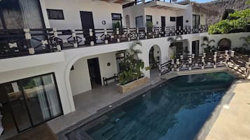 A resort with a pool, thatched-roof structures, and a multi-level building.