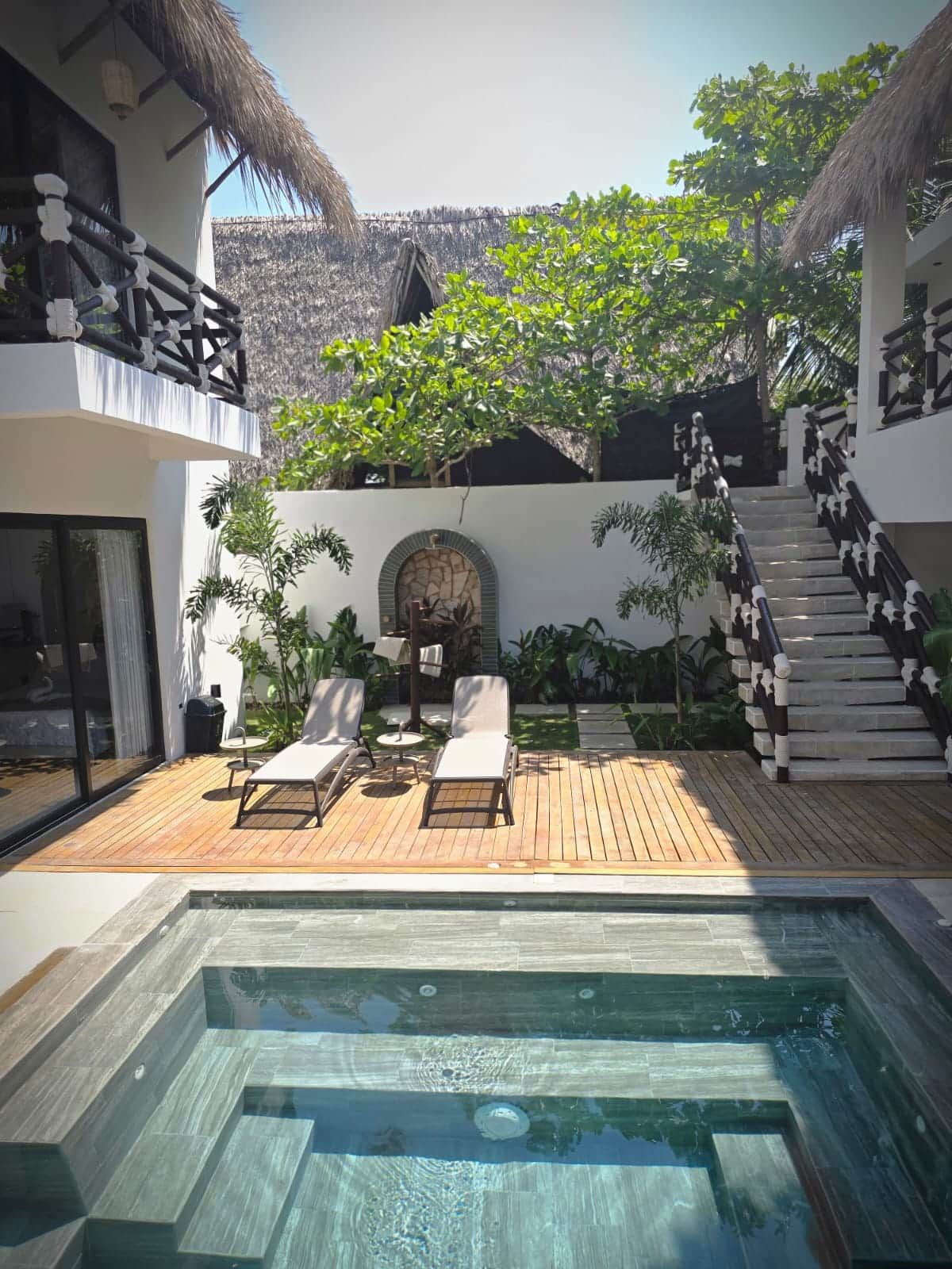Zona de piscina con sillas de descanso y una escalera que lleva a un edificio.