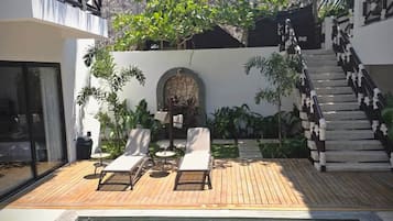 Uma área de piscina com espreguiçadeiras e uma escadaria que leva a um edifício.