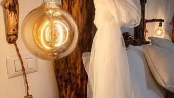Une pièce avec un lit, un luminaire suspendu et une chaise en bois.