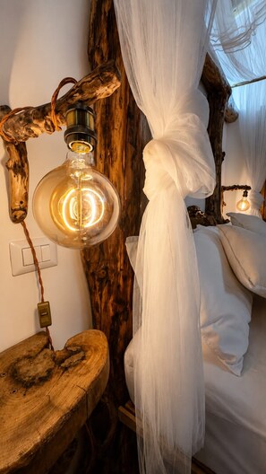 Een kamer met een bed, een hanglamp en een houten stoel.