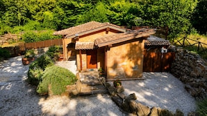 Uma casa japonesa tradicional com telhado de telhas, um caminho de pedra que leva à entrada e um jardim com plantas e um pequeno lago.