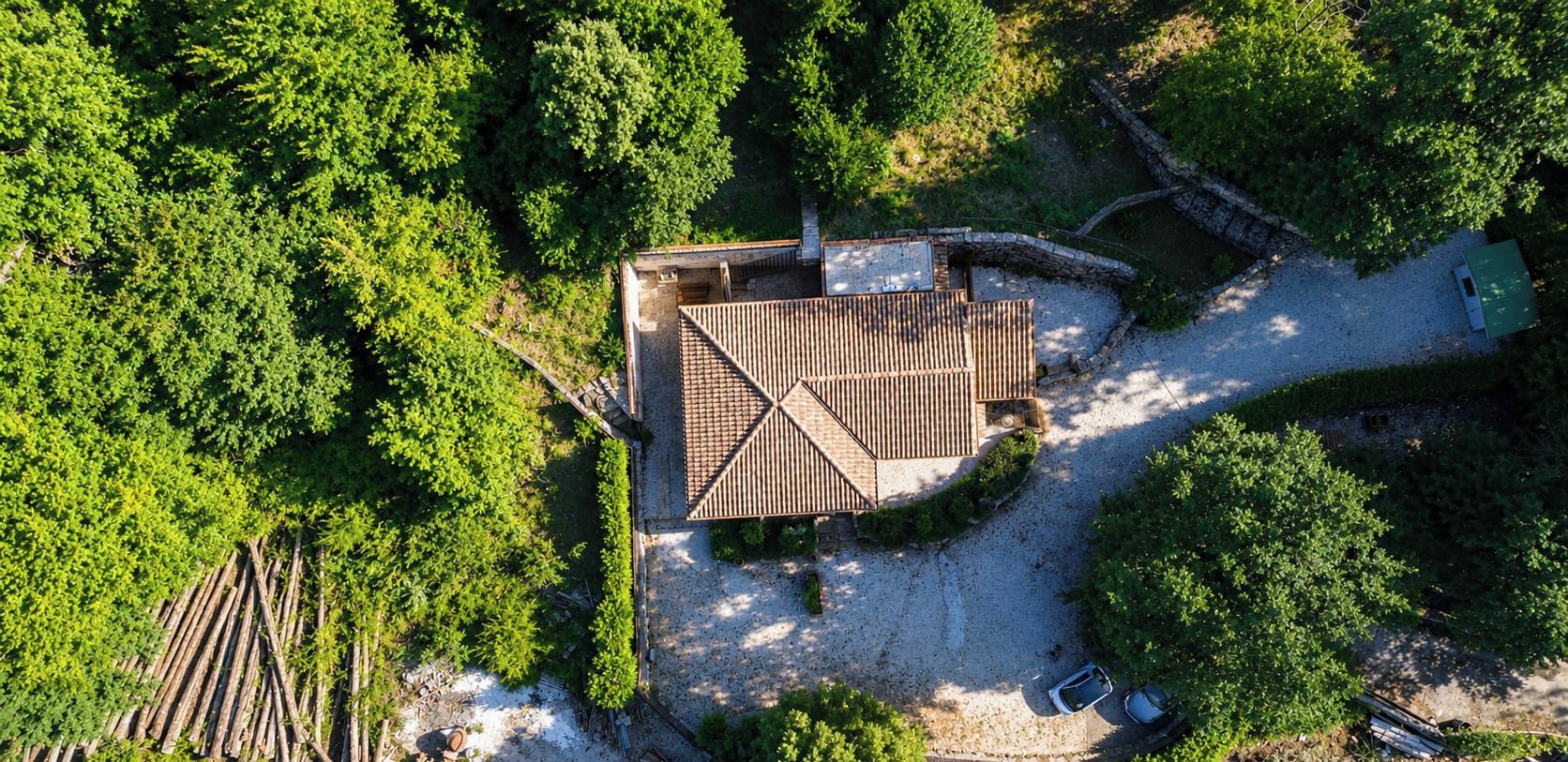 Vue aérienne d’une propriété dont le bâtiment principal est entouré d’une végétation luxuriante.