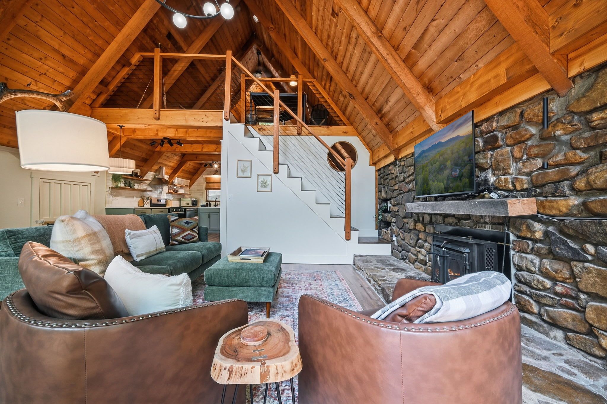 A cozy interior with a stone fireplace, a staircase, and a living area with leather sofas.