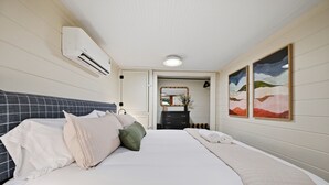 Una habitación de hotel con una cama, un tocador, un espejo y dos cuadros en la pared.