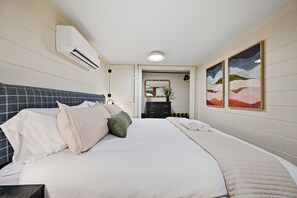A hotel room with a bed, a dresser, a mirror, and two paintings on the wall. - Dutch Creek A-Frame | Hot Tub, Fire Pit, Trailhead (Banner Elk)