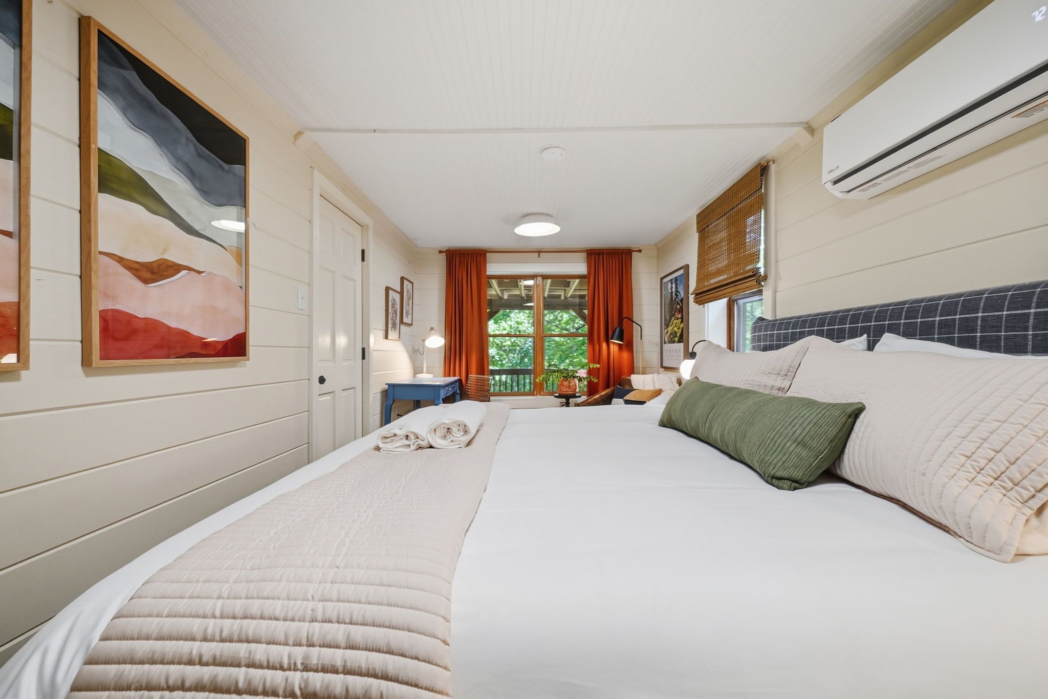 A hotel room with a large bed, a desk, a chair, and a window with curtains.