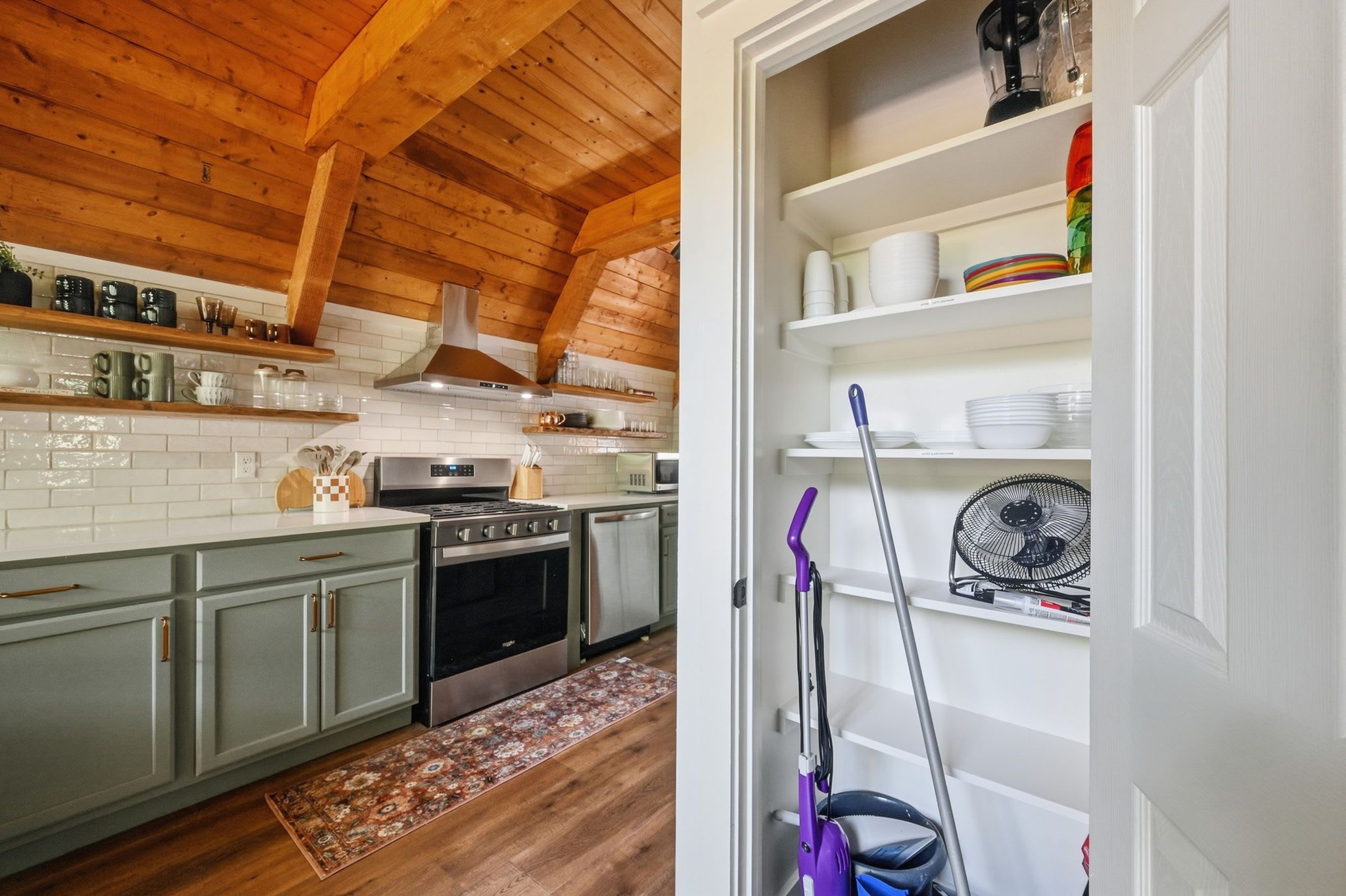 A kitchen with wooden beams, a stove, cabinets, and a microwave.