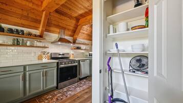 A kitchen with wooden beams, a stove, cabinets, and a microwave.