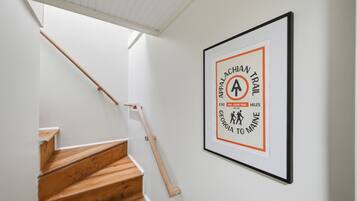 A staircase with wooden steps and a handrail, leading to a landing with a framed sign on the wall.