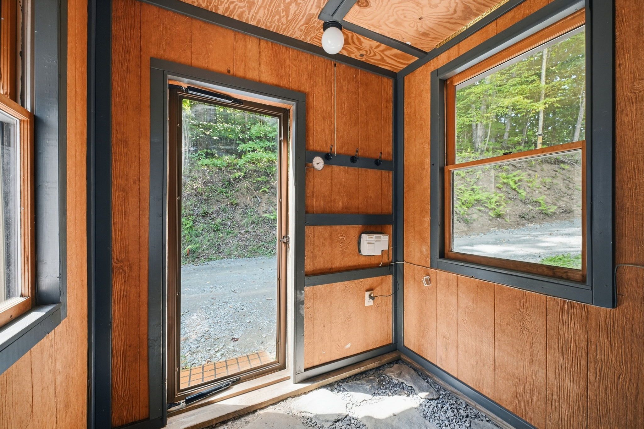 Ein Zimmer mit Holzwänden, einer Tür und einem Fenster.