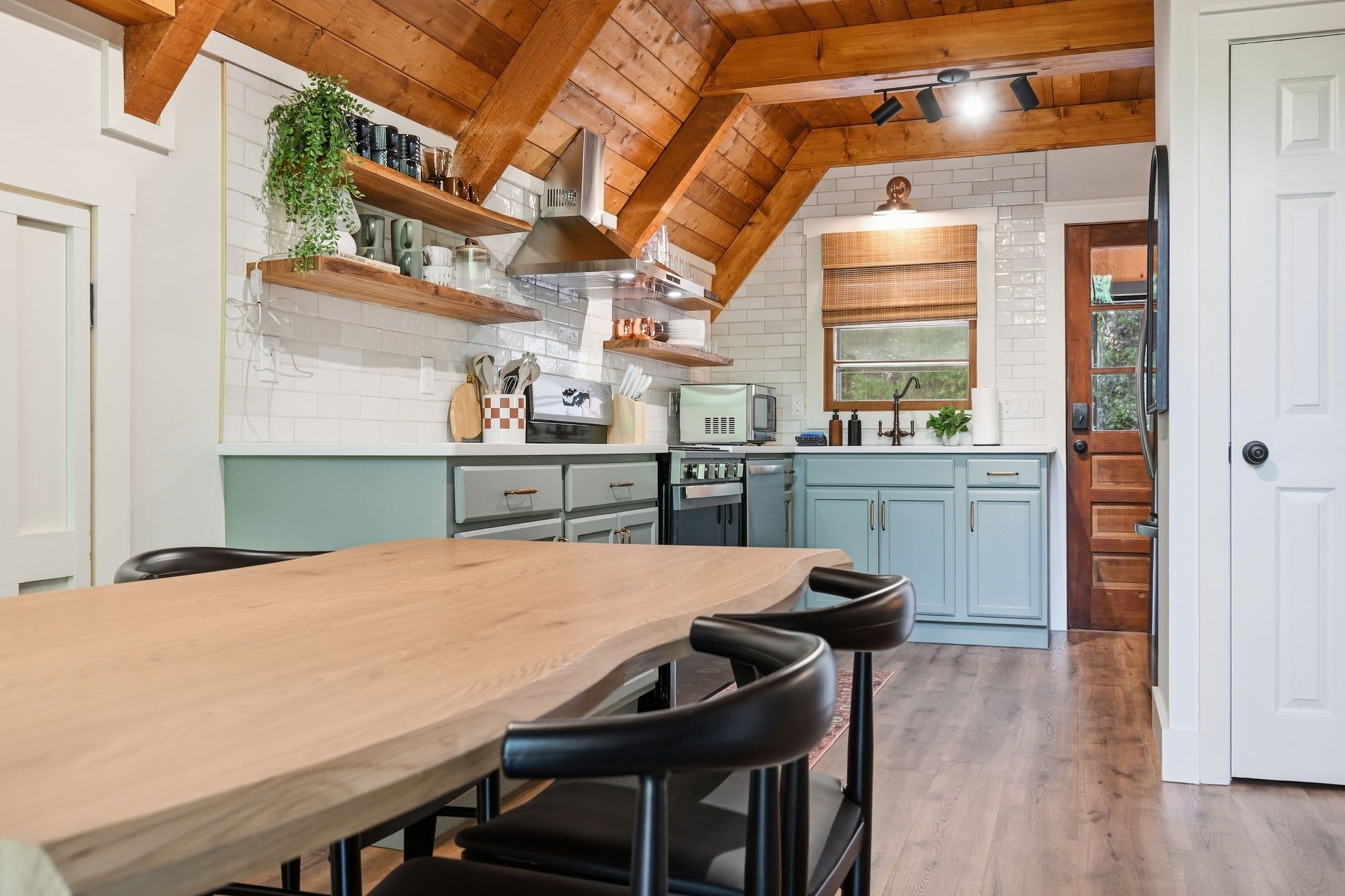 A kitchen with a wooden table, bar stools, a microwave, and a sink.