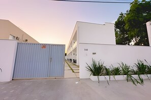 A gated entrance to a building with a white exterior and a sign indicating 'D-10'. - Apartamento 6 com 2 suítes 450m da praia (Santa Cruz Cabrália)