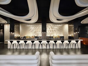 A modern bar area with a marble countertop, black bar stools, and a stone wall backdrop. - Modern 1BR with Breathtaking Yorkville View (Toronto)