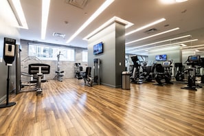 A gym with exercise equipment, wooden flooring, and a large window. - Modern 1BR with Breathtaking Yorkville View (Toronto)